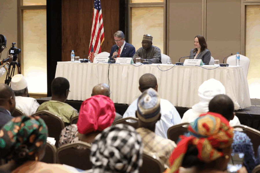 Panel discussion with speakers seated at a table addressing an audience at a formal meeting
